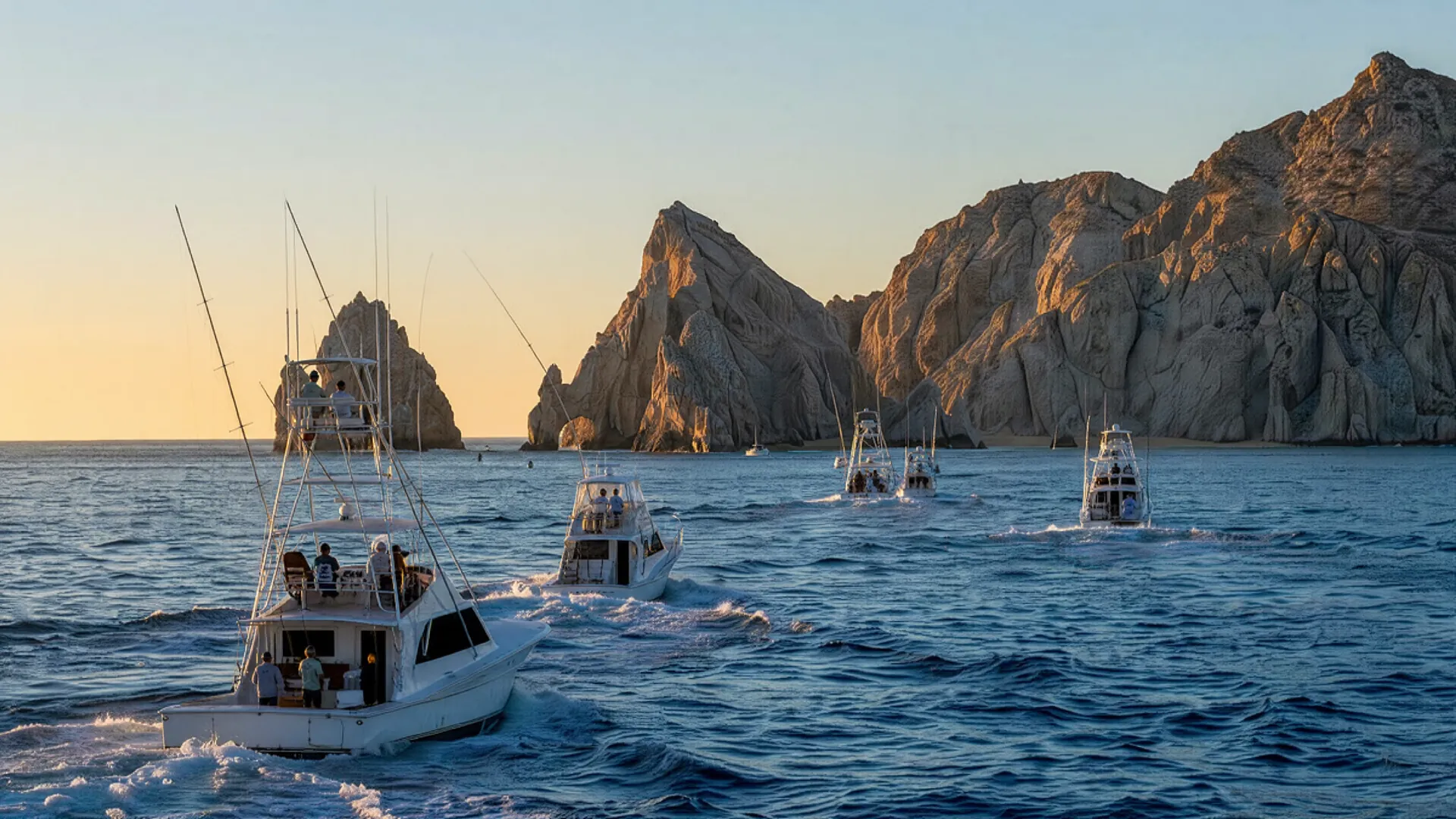 Varias embarcaciones de pesca deportiva zarpan al amanecer en aguas azules frente a los acantilados rocosos de Cabo San Lucas.